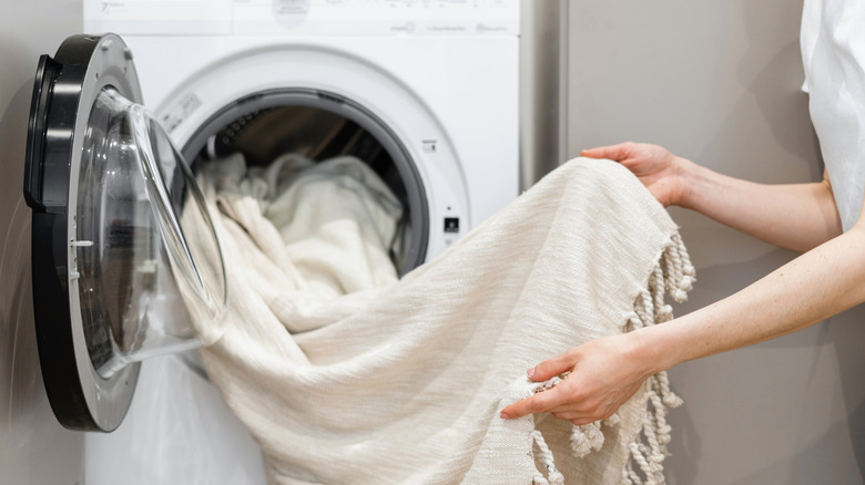 Person unloading white curtains with trim from washing machine