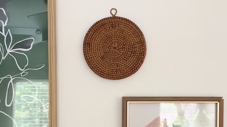 Round rattan wall decor hanging on the wall with framed art