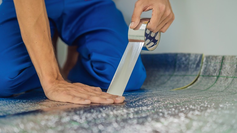 person installing hardwood underlayment