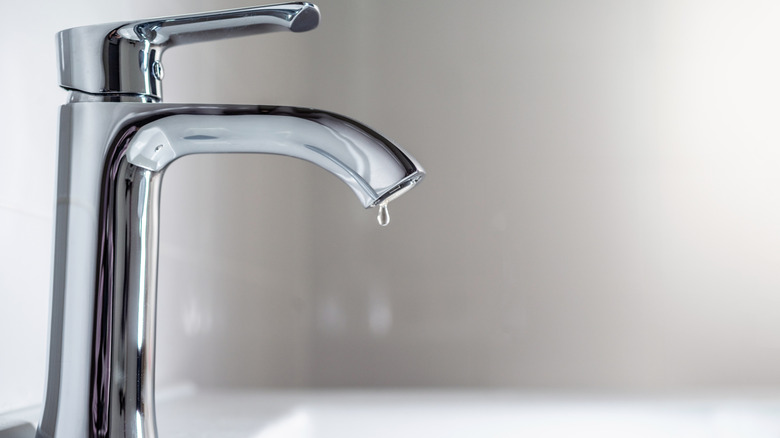 Water dripping from sink faucet in a bathroom