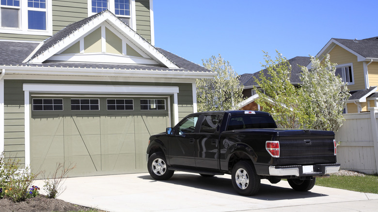 Black trucked parked in driveway of green residential home