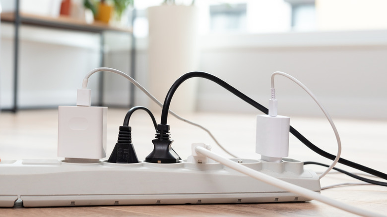 Electric cords left plugged into a power strip on a living room floor