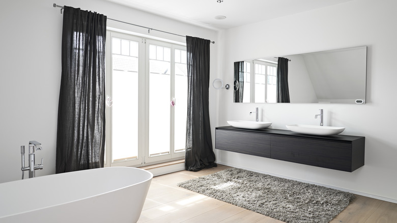 White bathroom with sheer black curtains.