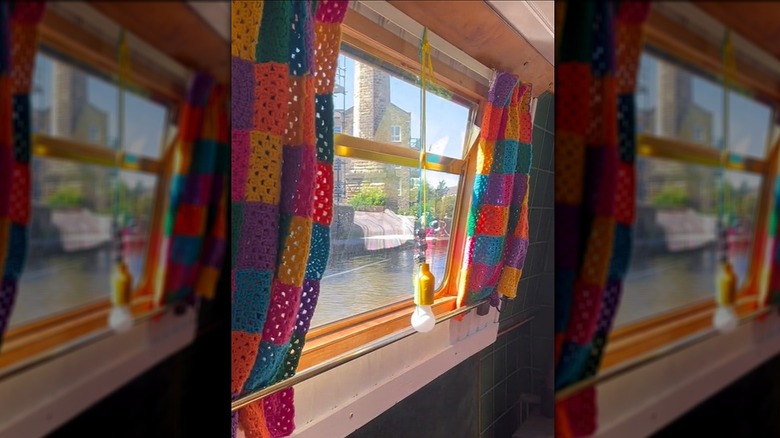 A crocheted set of granny square curtains in the living space of a boat