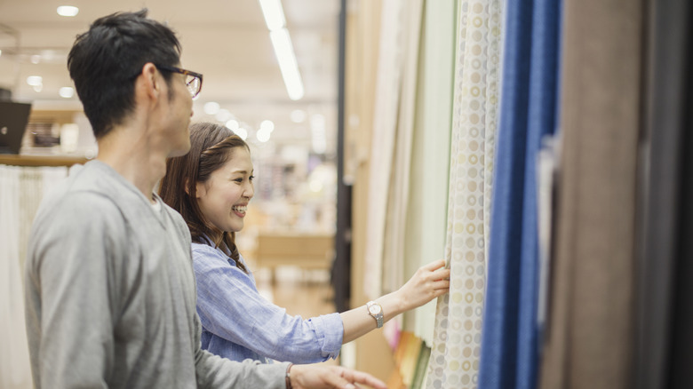 Couple looking at patterned curtains in store