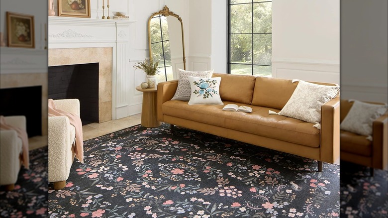 A black rug with nightingale and floral designs lays under a leather couch in a stylish living room