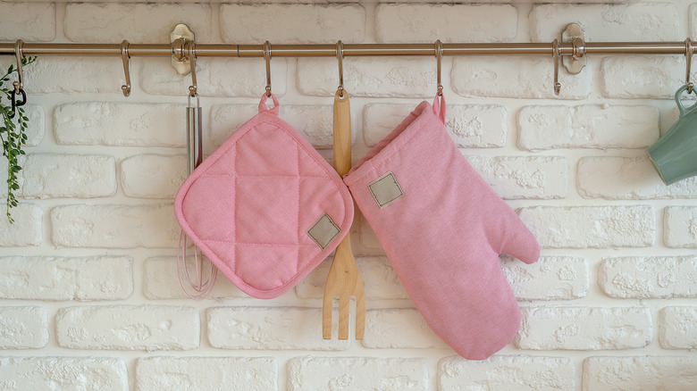 pink oven mitts hanging on rack