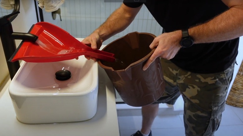 using dustpan to fill bucket