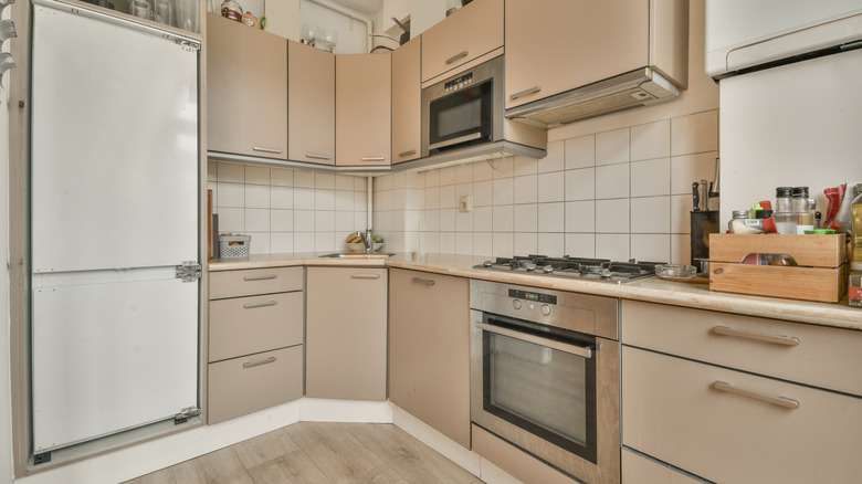 A kitchen with beige cabinets and white fridge