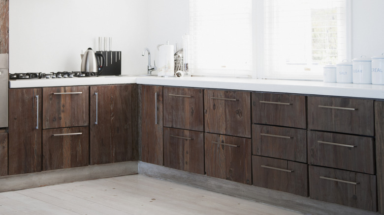 A kitchen with dark wood cabinets and white counters