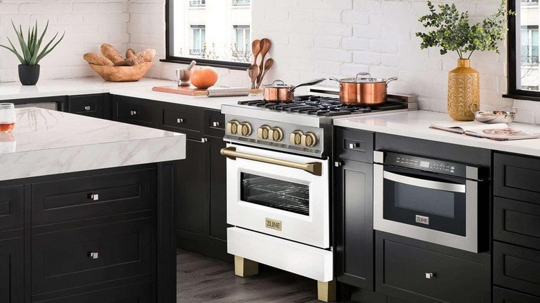 A kitche with black cabinets and white stove and countertops