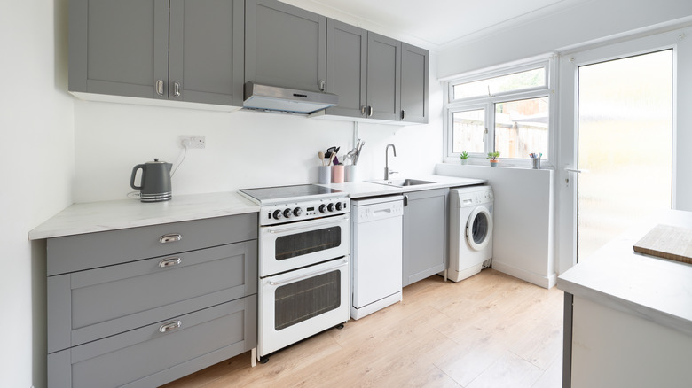 A kitchen with gray cabinets and white appliances