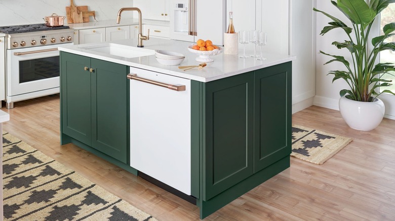 A kitchen with white appliances and a green island