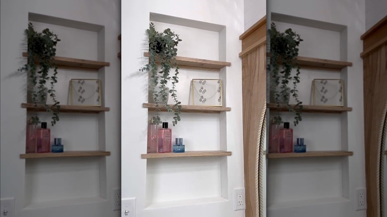 A recessed shelving unit fitted into a bathroom wall