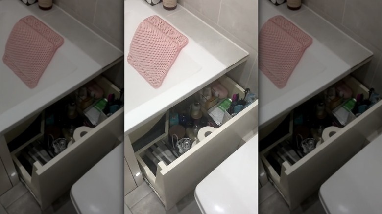 A bathtub with a built-in medicine cabinet made of kick drawers