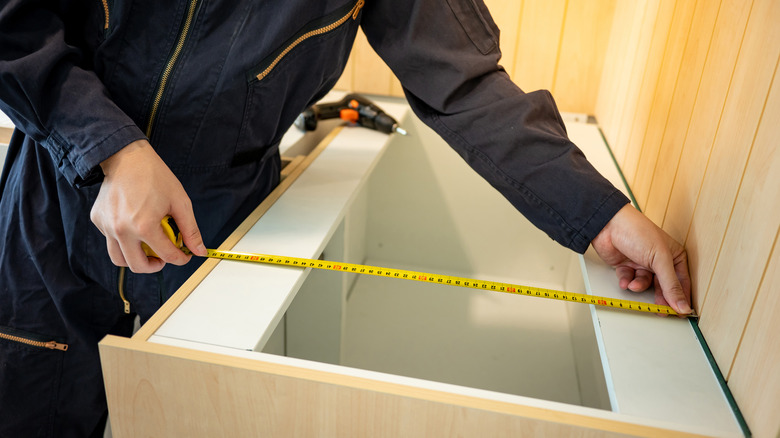 Person measuring kitchen cabinet widths