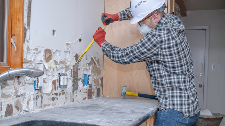 Man removing old backsplash