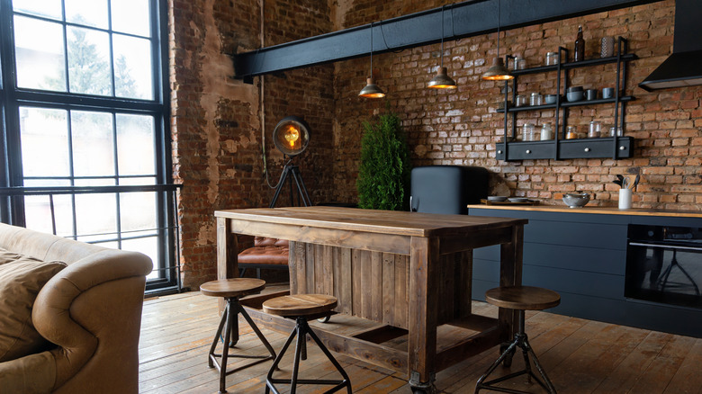 Industrial home kitchen with exposed brick wall and large wood kitchen island