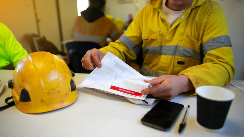 construction worker holding stack of paper