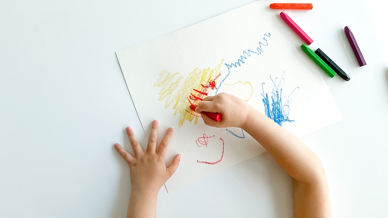 child drawing with crayons on a table