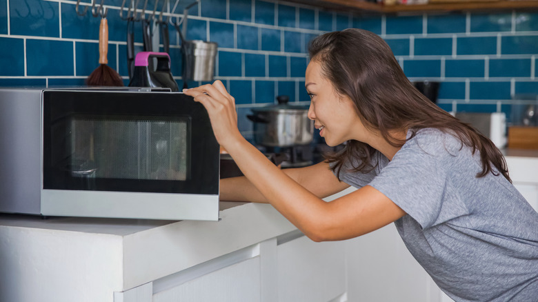 woman looking in a microwave