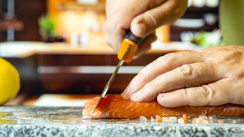 Hands cutting fish on granite countertop