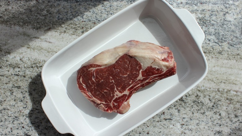 Raw meat in pan on granite countertop