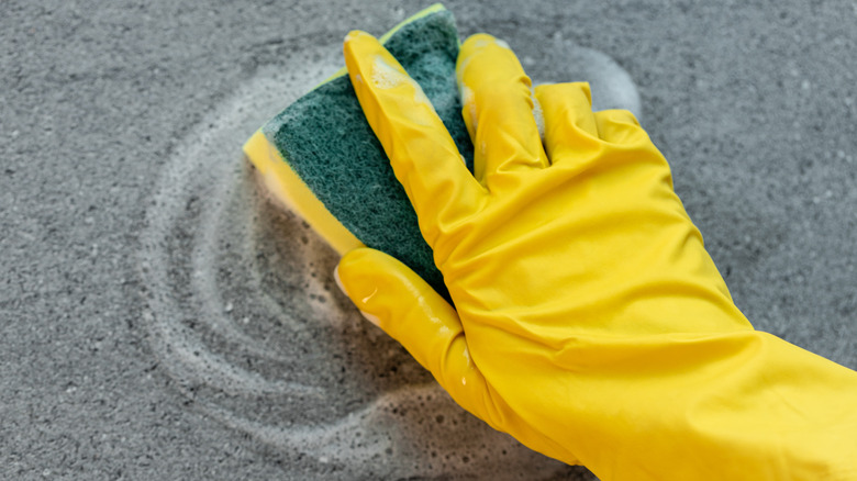 Gloved hand with sponge cleaning countertop