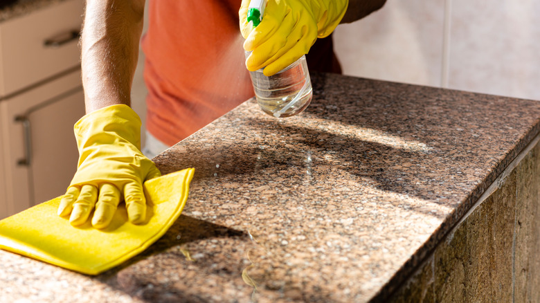 Person using a cleaner and cloth on granite