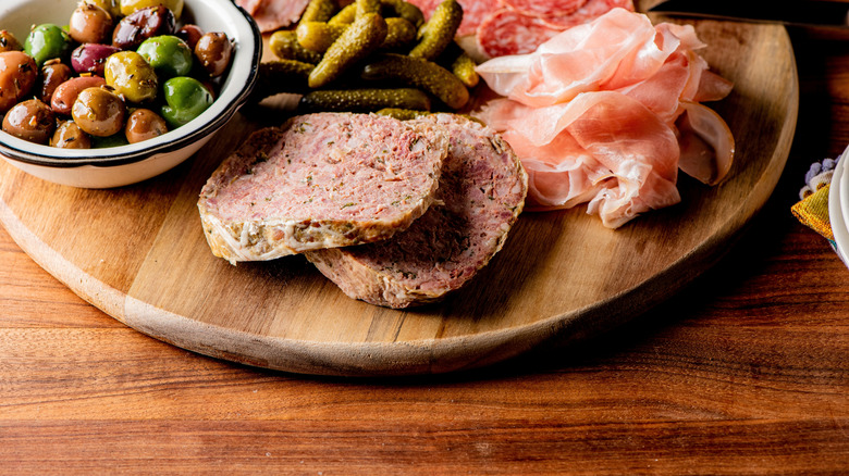 Wooden charcuterie board with food on a wooden table