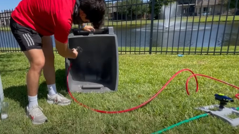 man hosing down trashcan