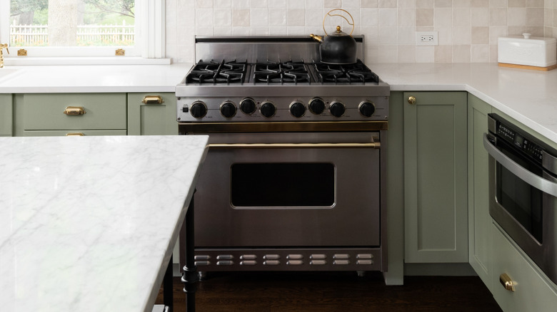 Kitchen with sage green cabinets and gold hardware