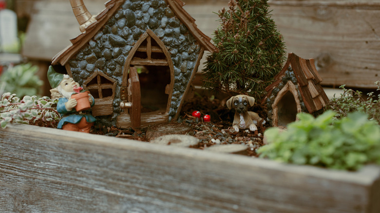 A miniature display with some stone cottages, a gnome and a little dog in an old drawer