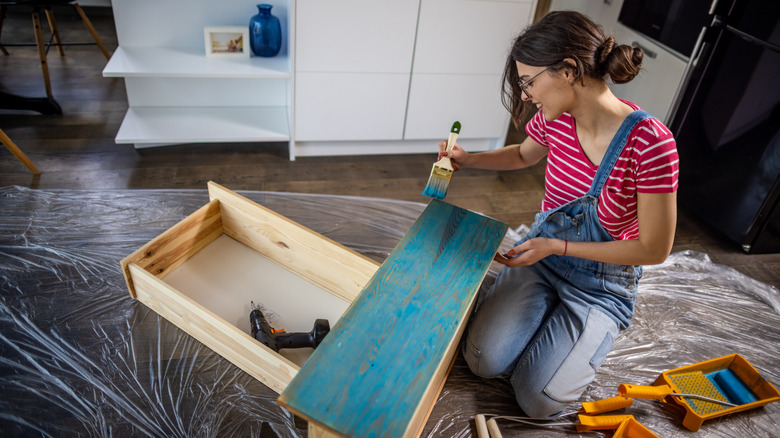 A woman painting some drawers in her kitchen