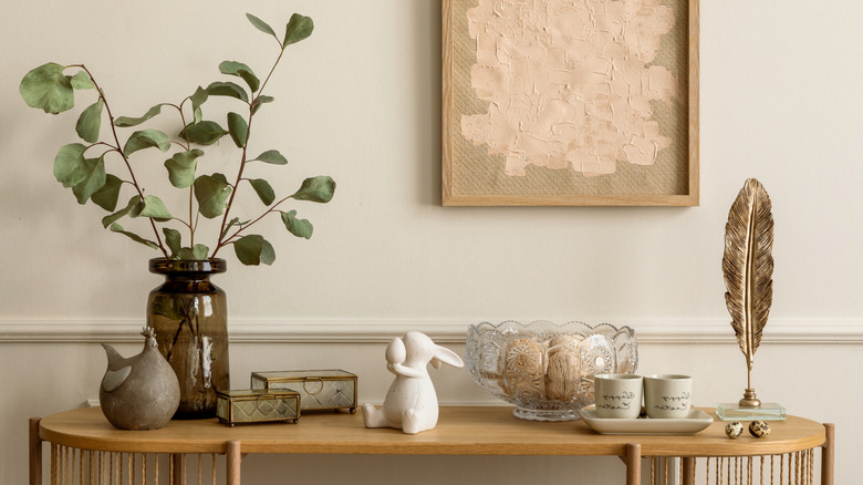 Entryway table with faux foliage and other decor pieces