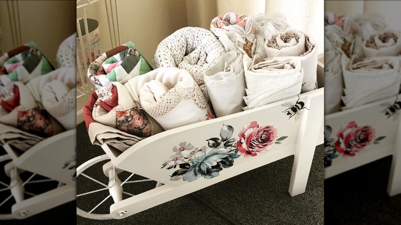 painted wood wheelbarrow holding linens