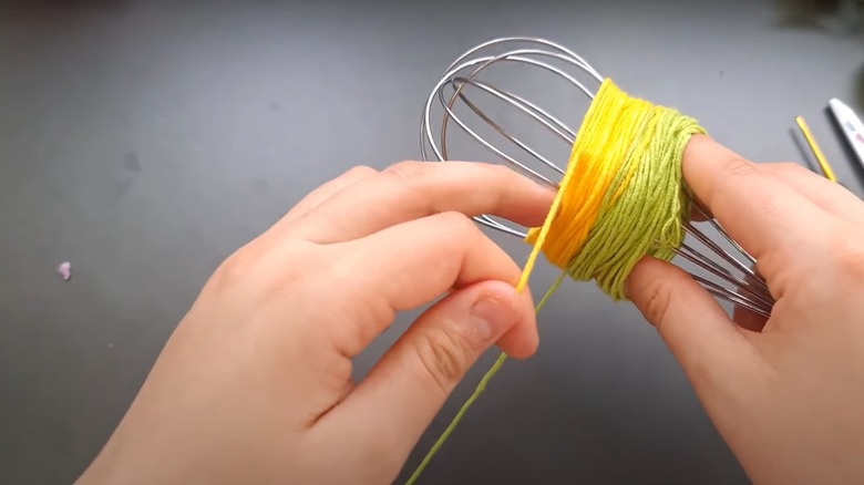 person wrapping yarn around whisk