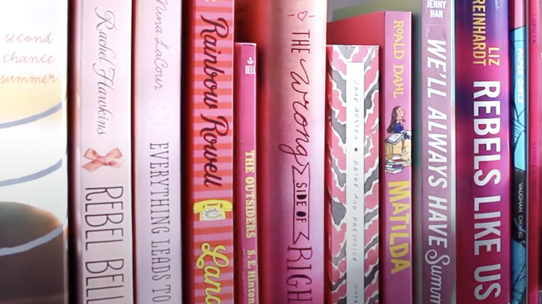 Pink books sitting on a shelf.