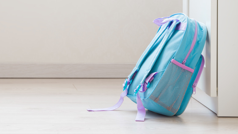 A kid's backpack lays on the floor.