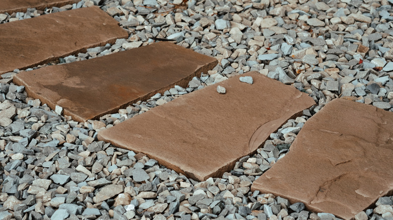 Brown natural stone pavers in gravel yard