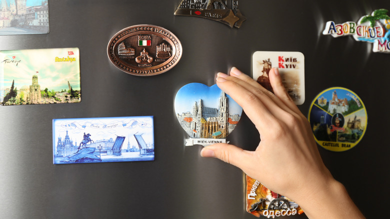 person touching magnets on fridge