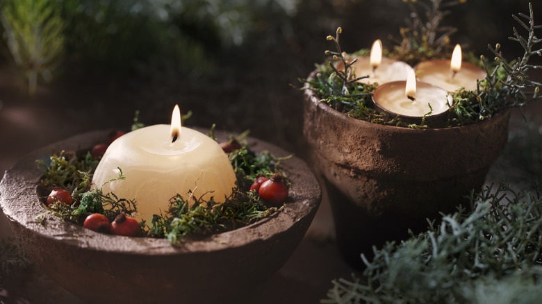 Terra cotta pots lined with moss hold candles for charming holiday display