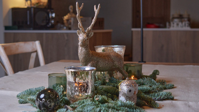 A silver reindeer and other woodland creatures create a playful nature-themed display with natural evergreen boughs.