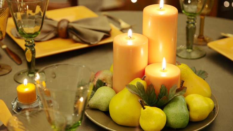 A table centerpiece holds golden and green pears and candles in glass holders.