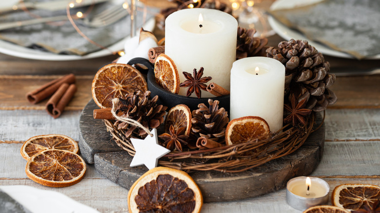 A centerpiece with dried orange slices, cinnamon sticks, and candles lends warmth and fragrance to the holiday table.