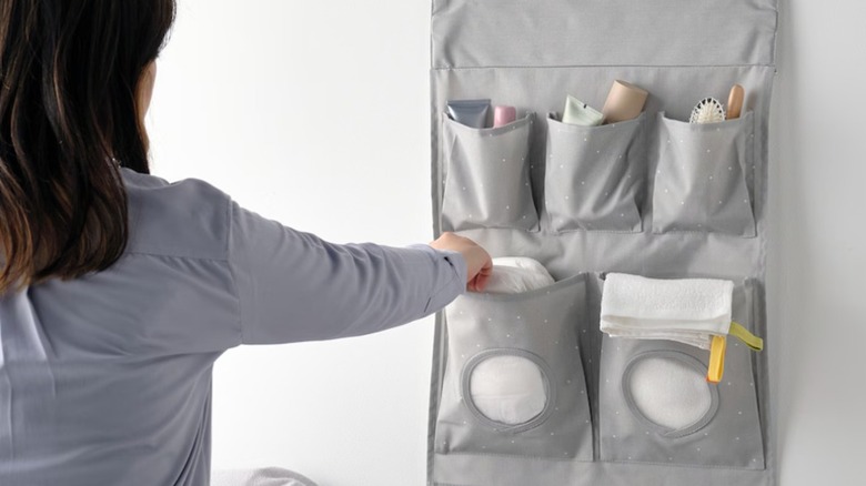 Woman grabbing a diaper from a gray hanging storage system