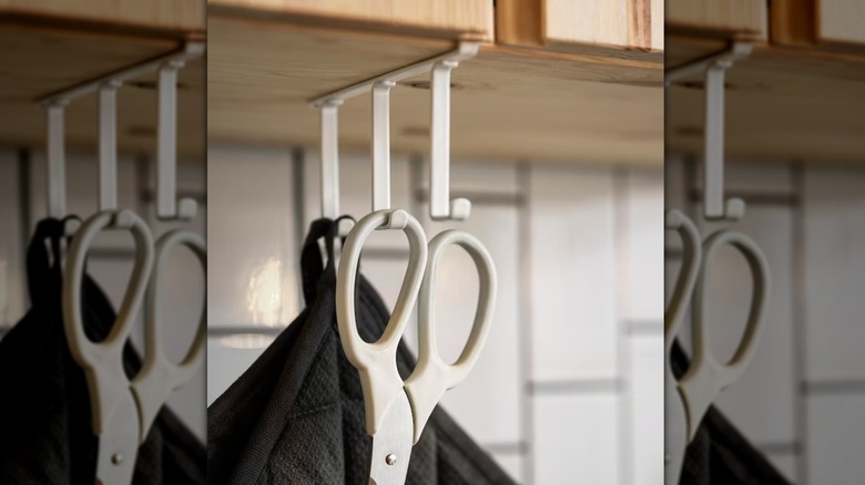 A white hook rack holding shears and an oven mitt