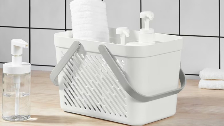 White plastic basket holding soap and a towel