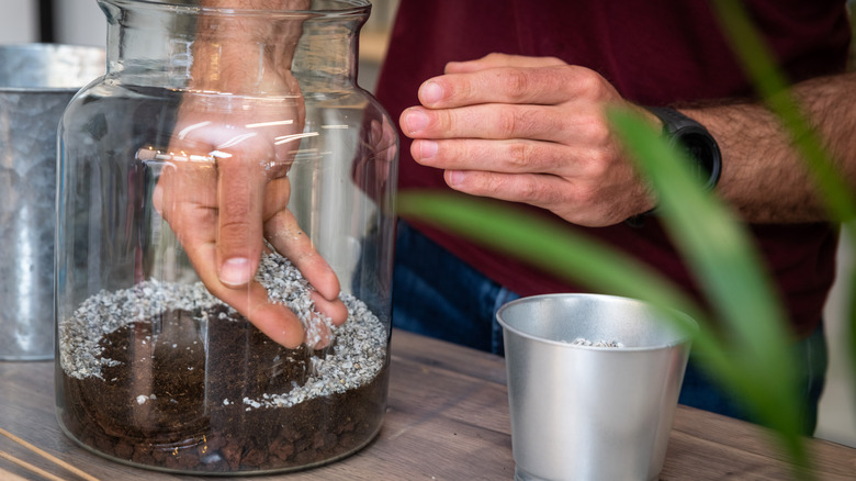 Gardener putting soil into jar