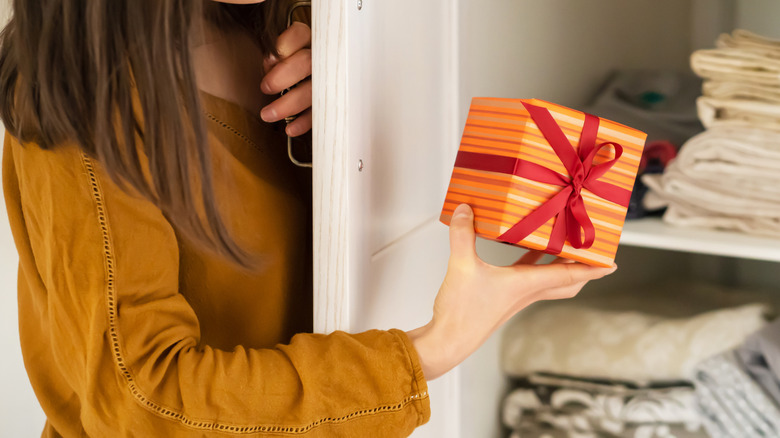 A woman holding a gift box by the closet